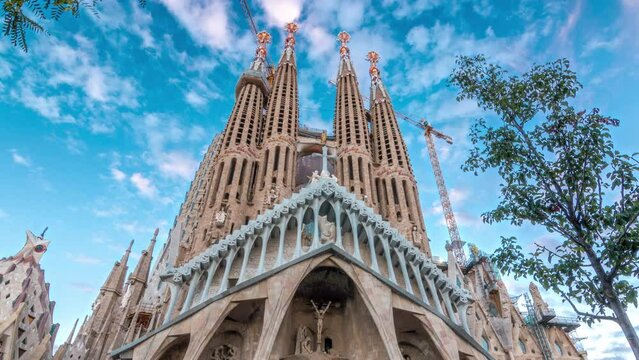 Sagrada Familia Timelapse Hyperlapse in Barcelona, Spain. The Enchanting Autumn Scene, Adorned with Green Trees Against a Picturesque Blue Cloudy Sky