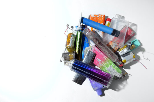 A collection of broken discarded electonic cigarette vapes that have been collected from roadsides. Shot on a white worktop.