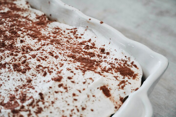 Homemade tiramisu cake on tray on white wooden table top view.