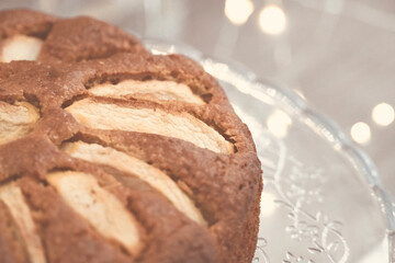 Homemade sliced fruit cake on white table with lights in the background.