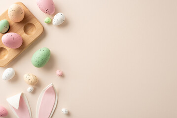 Obraz na płótnie Canvas Easter sweetness captured from above. Traditional eggs in wooden holder, adorable bunny ears adorn a pastel beige background—perfect for your personalized text or promotional message