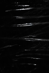 Abstract background. Polyethylene shine. Sparkling drops. Synthetic shine on black