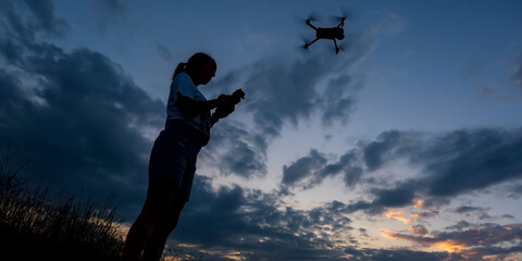 silhouette of woman controlling  drone on sunset background
