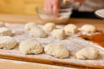 A woman forms pieces of dough for making donuts. The process of making donuts