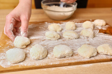 A woman forms pieces of dough for making donuts. The process of making donuts