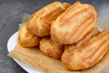French eclairs filled with vanilla cream on gray background.