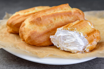 French eclairs filled with vanilla cream on gray background.