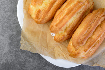 French eclairs filled with vanilla cream on gray background.
