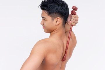 A topless asian man using a backscratcher to scratch a acnestis. Isolated on a white backdrop.