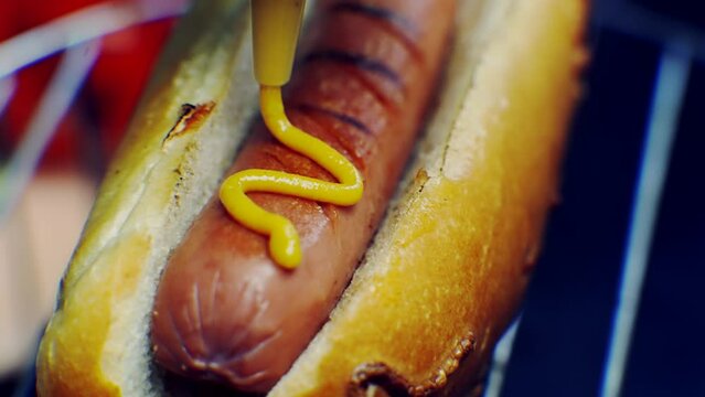 Tasty hot dog with grilled sausage . Adding mustard to hot dog	