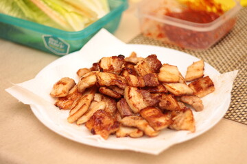 Slices of roasted bacon cut into small pieces served on a white plate