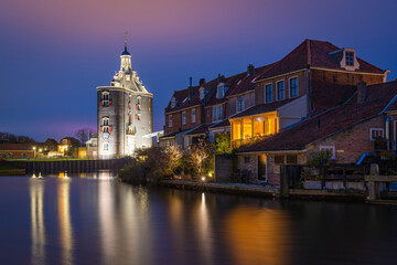 Cityscape of Enkhuizen in the evening, view of the historical city gateway Drommedaris by the canal
