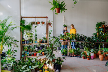 Botanical Shop Consult: Female Caucasian Customer and Asian Seller Discussing Plant Choices. Botanical Inspection: Examining Plant Variety in Flower Store.