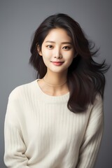 A radiant snapshot of a Korean beauty with light makeup, wearing a relaxed sweater and jeans, emanating charm and simplicity in a studio setting.