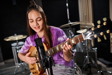 Fototapeta na wymiar jolly adorable teenage guitarist in vivid casual outfit plying her guitar and singing song