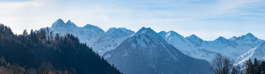 Panorama view landscape background of mountains with snow and forest trees in winter in in the Allgäu alps
