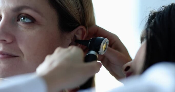 Otorhinolaryngologist examining patient ear with otoscope and checking hearing in adults. Diagnosis and treatment concept otitis inflammation ear concept