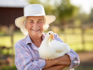 Cheerful farmer holding duck in his arms