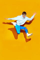 Fototapeta na wymiar Dynamic fashion moment as young man leaps in modern, comfy attire against striking yellow background. Style meets action. Concept of fashion and beauty, trends, shopping, sales season. Ad
