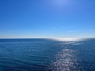 Blue sea glittering water and clear sky on horizon 