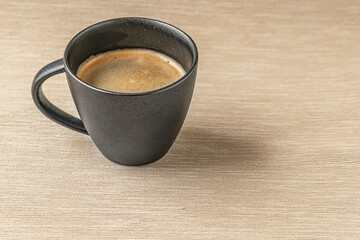 aromatic freshly brewed coffee in a black ceramic cup on a burlap cloth