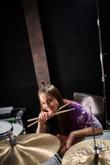 cheerful pretty teenage girl in vibrant attire preparing to play drums and looking at camera