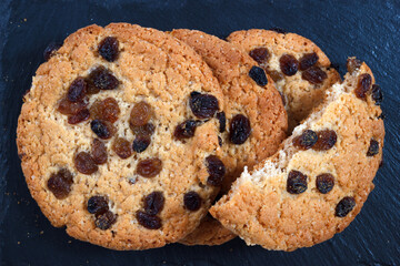 Americano cookies with raisins. The closeup view from above with black slate plate background. - 702748948
