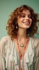 A smiling young model wearing a boho-chic maxi dress, accessorized with statement jewelry, against a solid light mint green background.