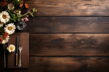 Forks, knives, flowers and place cards on a rustic wooden table.