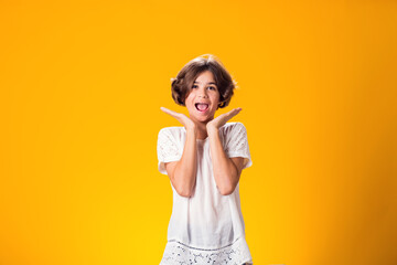 Surprised kid girl over yellow background. Astonishment concept