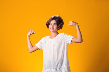 Smiling kid girl showing success over yellow background. Luck concept