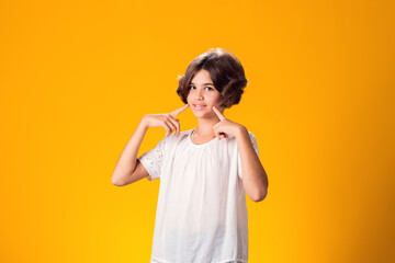 Smiling kid girl over yellow background. Emotion concept