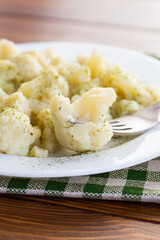 Cooked cauliflower, steamed, in a plate with spices .