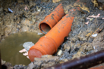 plastic orange waste pipes and a pool of water, construction site, closeup view