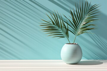  a white vase with a plant in it on a table with a shadow of a palm tree on the wall behind it.