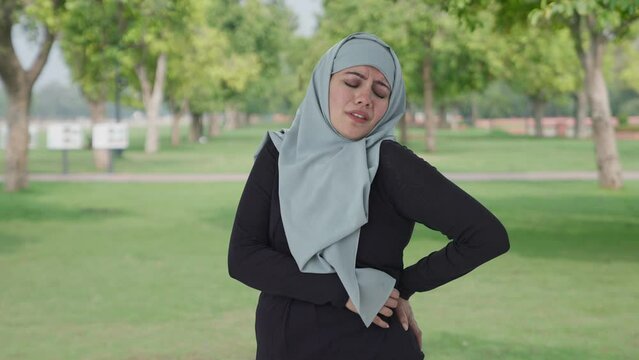 Sick Muslim woman suffering from Back pain in park