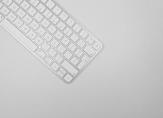Top view of white keyboard on light grey background. Modern office flat lay, copy space.