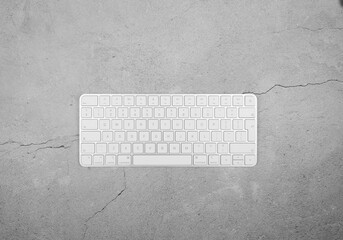 Top view of white keyboard on concrete background. Modern office flat lay, copy space.