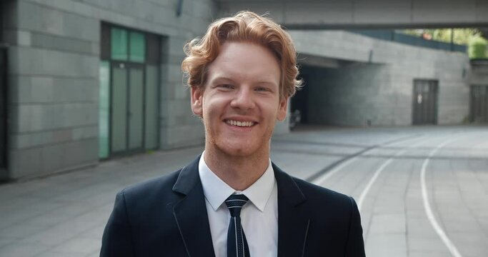 Businessman in luxurious suit smiles at camera in close-up success evident in demeanor. Smile reflects success he's achieved. Moment of success captured in expression reveals his inner confidence.