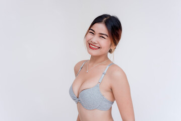 A confident southeast asian woman wearing only gray bra. Half body shot isolated on a white backdrop.