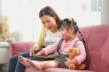 young asian female using tablet with her kid,mother spend free time on weekend together with a...