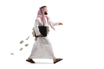 Full length profile shot of a suadi arab man walking with a briefcase full of money
