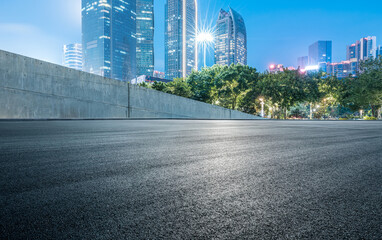 Empty asphalt road and cityscape at night