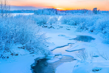 Winter frosty landscape.  Landscape with  river and snowy forest in Western Siberia. Freezing river against sunset background.