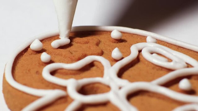 Cookies or gingerbread are covered and decorated with white sugar icing from a pastry bag during cooking