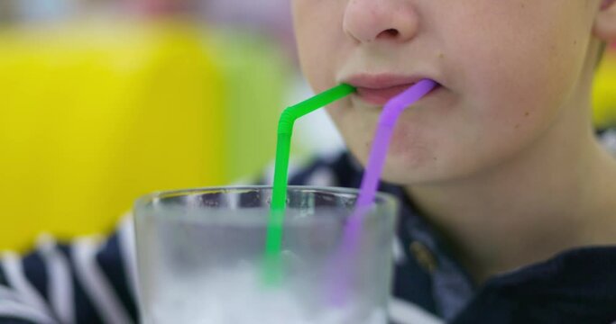 Closeup of little child drinking Mojito with straw in a fast food restaurant
