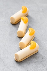 Vegan Tangerine cream dessert bars on cookies. Decorated with tangerine slices. LIght gray background	