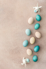 Colorful Easter eggs and cute bunnies on a pastel pink background, top view, copy space