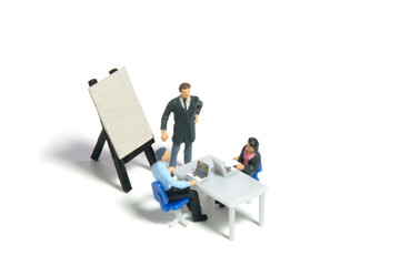 Miniature tiny people toy figure photography. Teamwork brainstorming concept. Small group employee gathers for work discussion. Isolated on a white background