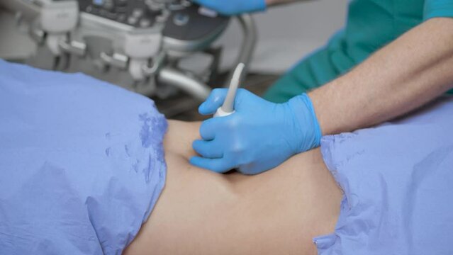 Medical Ultrasound suite. A sonographer scanning a female abdomen with an ultrasound probe.